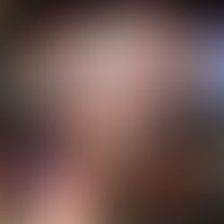 Hand holding the book "The Violently Departed" by Sarah J. Daley, featuring a skull with red flowers, in front of colorful bookshelves.