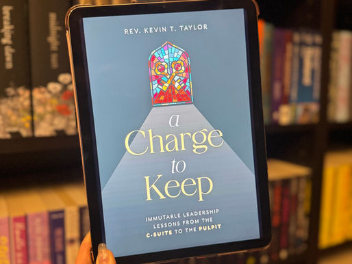Person holding a tablet displaying Rev. Kevin T. Taylor's book "A Charge to Keep" in front of a colorful bookshelf.
