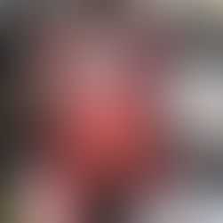 A hand holds a book titled "Running Close to the Wind" by Alexandra Rowland. The cover features red floral designs and a ship, set against bookshelves.