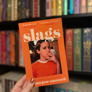 Hand holding book with orange cover titled "Slags." Woman on cover smokes. Background: colorful bookshelf. Moods: playful, rebellious.