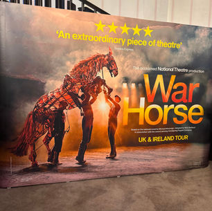 Banner for "War Horse" UK & Ireland tour. Features horse puppet with three handlers, glowing lights, and text: "An extraordinary piece of theatre."