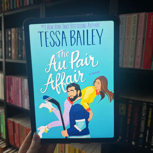 E-reader displaying "The Au Pair Affair" by Tessa Bailey, held by a hand. Bright blue cover with illustrated couple. Background: bookshelves.