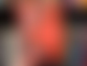 Hand holding an orange book titled "A Slow and Secret Poison" by Carmella Lowkis, with botanical art, in front of a colorful bookshelf.