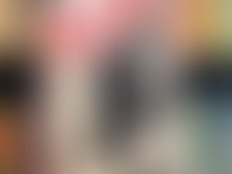 Hand holds "Borderline Fiction" book by Derek Owusu. Bold red and black design with a silhouette. Bookshelf background with colorful spines.