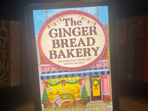 Hand holding a tablet displaying "The Gingerbread Bakery" cover with festive bakery illustration. Background shows blurred books on shelves.