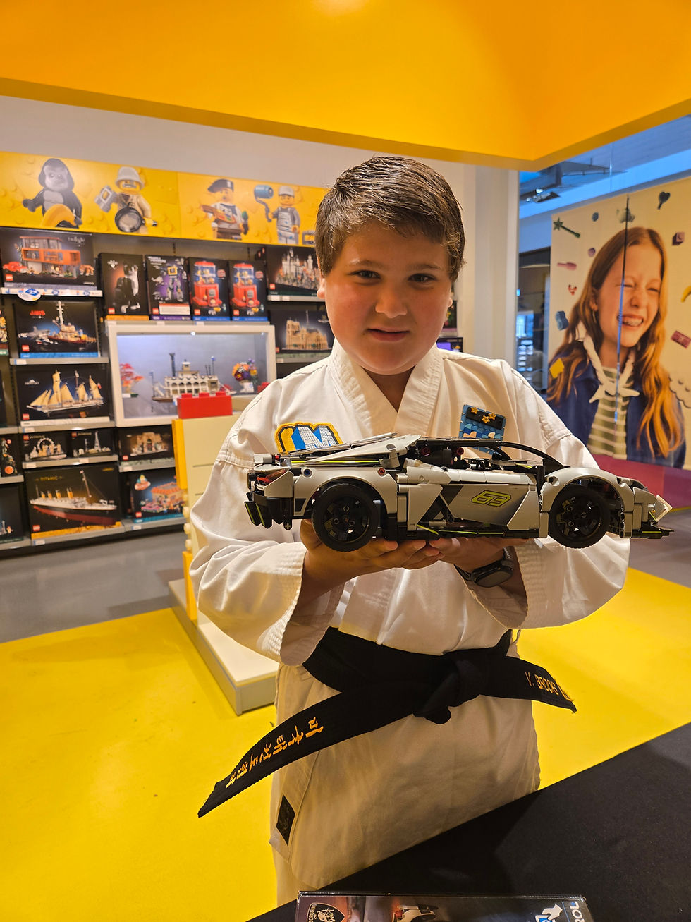 Boy in karate gi holding custom lego models eugene car.
