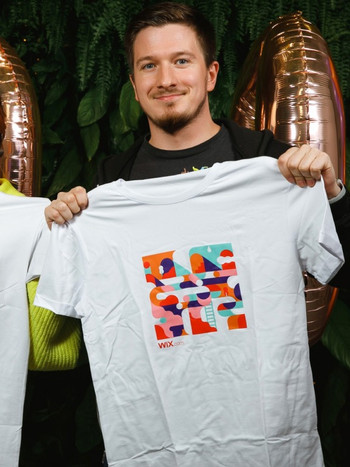 A Wix employee from Dnipro holding a white Wix T-shirt