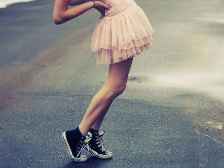 young woman standing in street with tennis shoes on