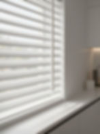 White faux wood Venetian blinds on a kitchen window