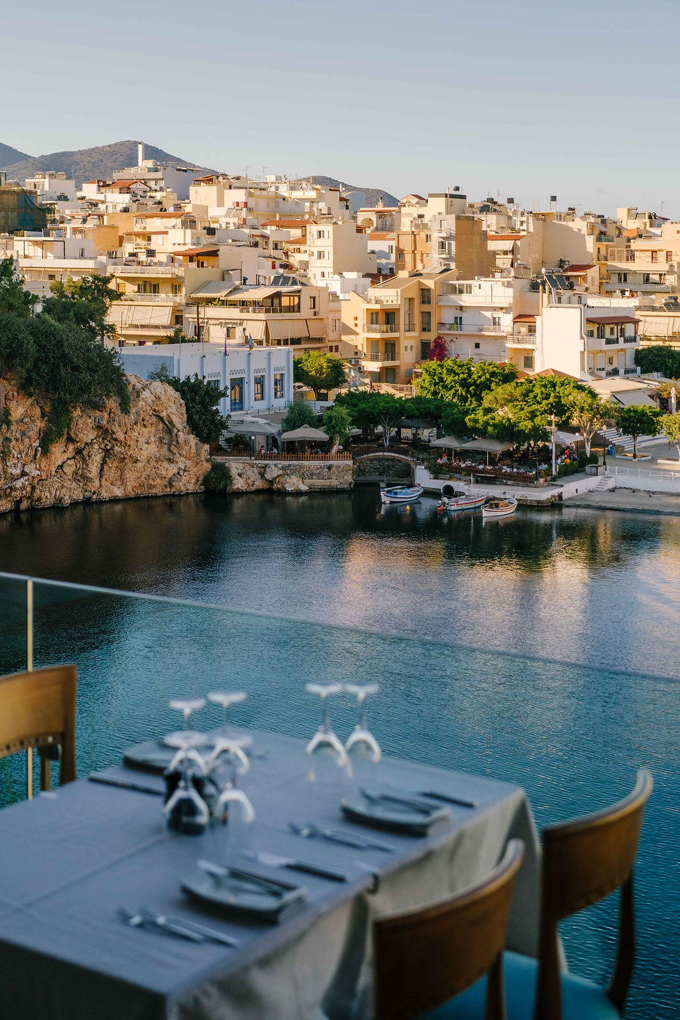 Dinner table with wine glasses overlooking the water of Agios Nikolaos, Crete.