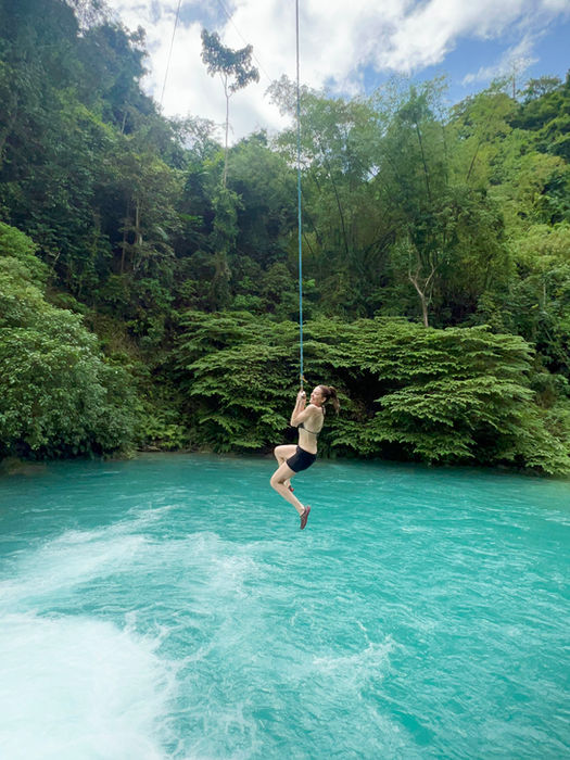 Solo traveler swinging over a blue lagoon in the Philippines