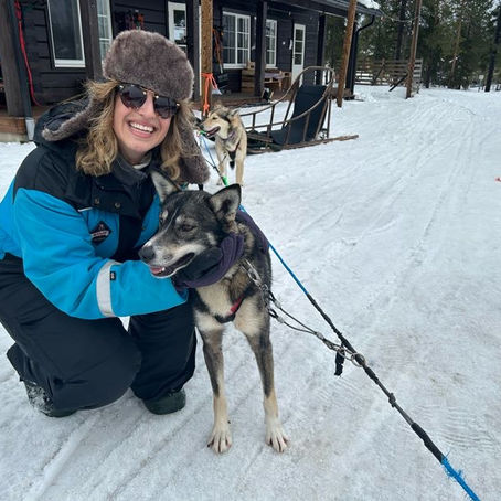FTLO traveler alum hugs a sled dog on a Lapland trip