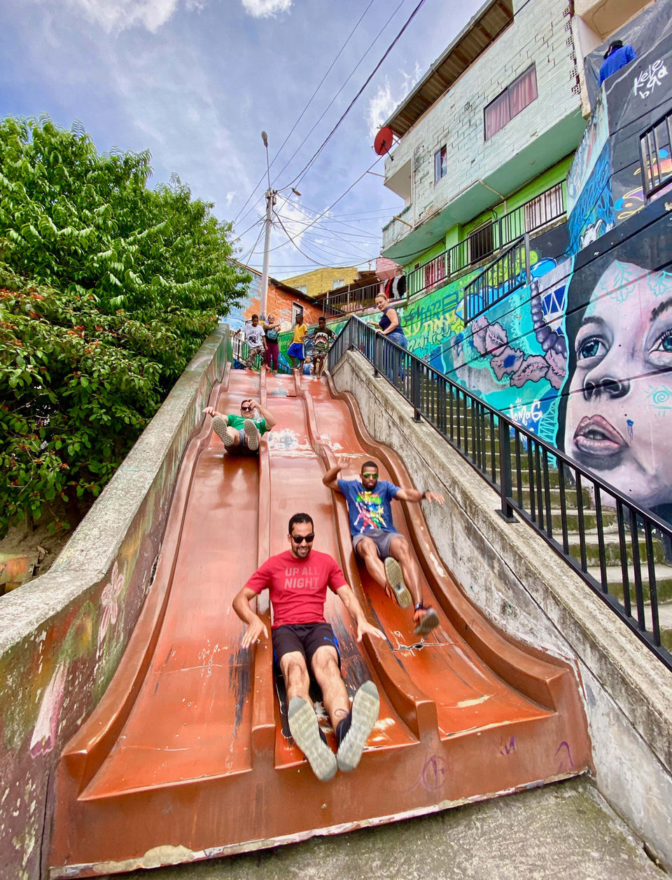 Travelers slide down a colorful outdoor slide in Medellín’s Comuna 13