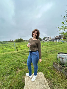 solo traveler posing at a vineyard with a glass of wine in hand