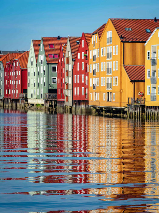 Colorful wooden houses reflected in the water in Trondheim