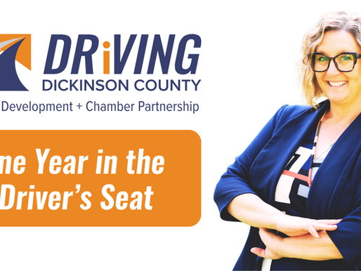 Natalie Muruato, President and CEO of Driving Dickinson County, stands beside the organization’s logo in a feature graphic marking her first year leading the organiza