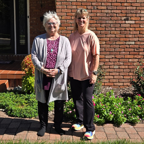 Mary Alexander and Shelly Crane standing together outside a brick home in Abilene, Kansas.