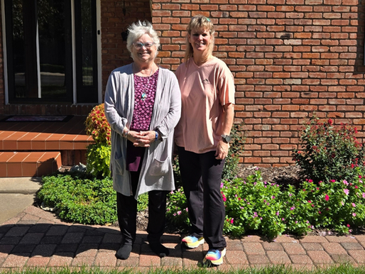 Mary Alexander and Shelly Crane standing together outside a brick home in Abilene, Kansas.
