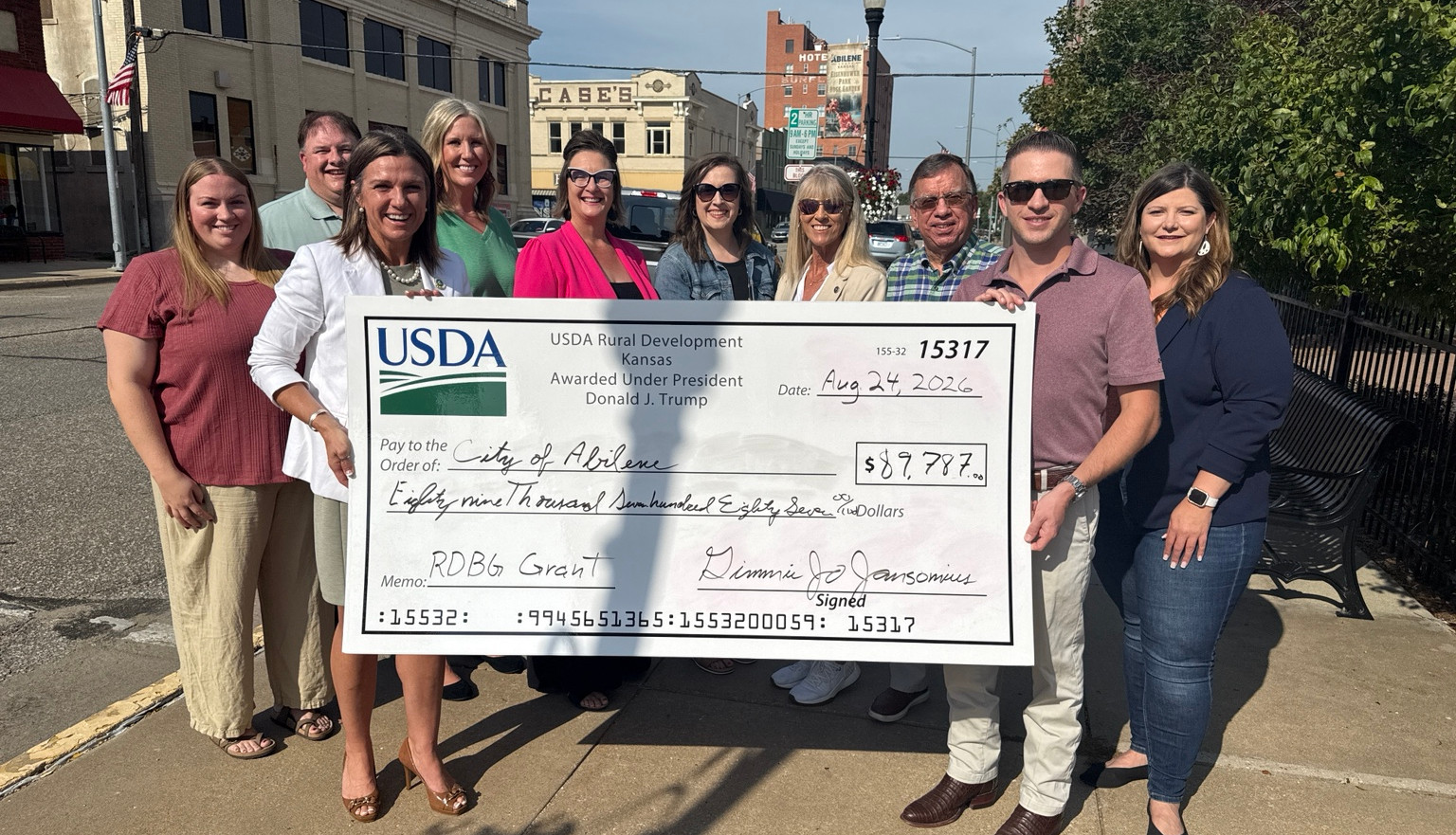 Representatives from the City of Abilene, Driving Dickinson County and community partners gathered to recognize an $89,787 USDA Rural Business Development Grant awarded to the City of Abilene for the Rural Business Accelerator Program. Holding the check, from left, are Gimmie Jo Jansonius, USDA Rural Development State Director, and Abilene Mayor Brandon Rein. Behind the check, from left, are Baillee Youk of Driving Dickinson County; Austin Britt, DDC Board Member; Kari Zook, DDC Board Member; DDC President and CEO Natalie Muruato; Julie Roller Weeks, Director of the Abilene Convention & Visitors Bureau; Elizabeth Weese, Executive Director of Community Foundation of Dickinson County; Tony Geiger, DDC Board Member; and Jackie Hynes of Events and Marketing Director of Driving Dickinson County.