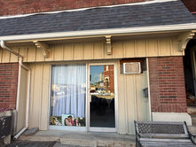 Michela Brown Photography storefront with a branded glass door, portraits displayed in the front window, and a bench outside.