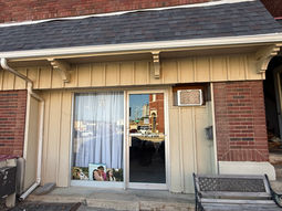 Michela Brown Photography storefront with a branded glass door, portraits displayed in the front window, and a bench outside.