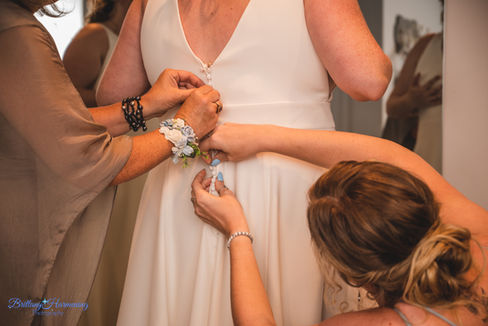 Mom and Sister helping bride into dress