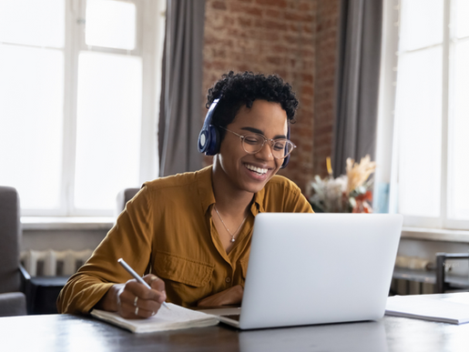 a person wearing headphones taking a course on a computer and taking notes