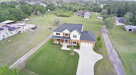 Aerial view of modern house, long driveway, and green lawn
