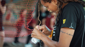Volleyball coach repairing a net by hand using rope at a grassroots training session
