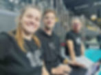Marketer Jitka smiling at the camera, accompanied by two men (both LKTBF volunteers). All wearing LKTBF tops and sitting in an indoor volleyball sports hall