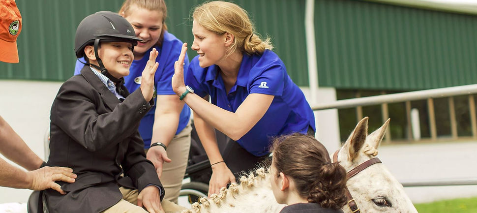 Image: A rider giving an NVTRP instructor a high-five on horseback.