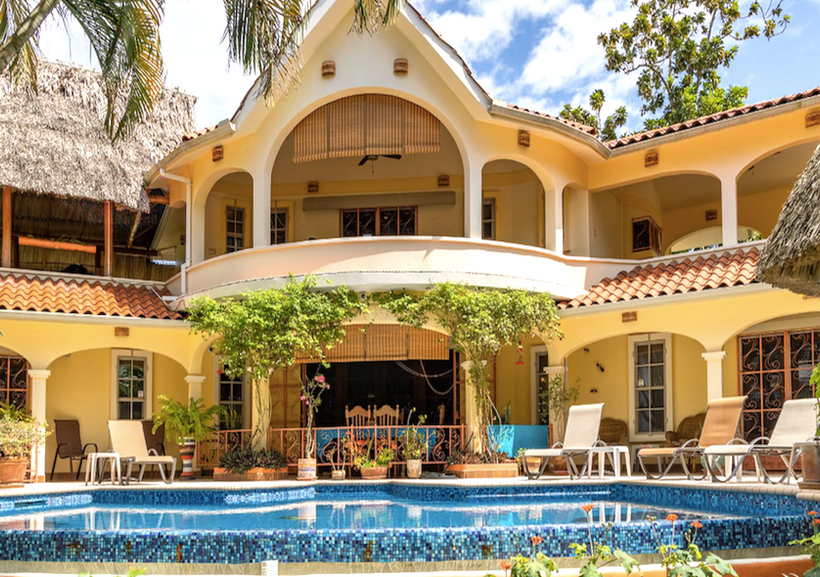 Front-facing view of Villa Attalea’s pool, tropical gardens, and arched main terrace