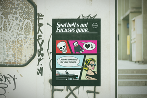 "Seatbelts on! Excuses gone." PSA poster with comic art style.