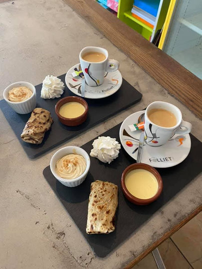 Café gourmand avec gâteaux et crèmes sur un plateau noir, vue de dessus.
