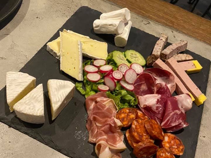 Plateau de fromages et charcuterie variés et colorés sur une table.
