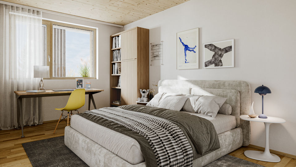 Ein eingerichtetes Schlafzimmer mit einem Schreibtisch vor dem fenster rechts, einem Bett und daneben einem kleinen Beistelltisch mit Lampe. Auf der Wand hängen zwei Bilder mit abstrakter Kunst. Im Eck steht ein Bücherregal.