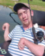 Man with cap and striped shirt fishing near lake with.