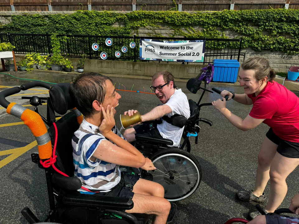 Three people enjoy water guns, with visible excitement outdoors