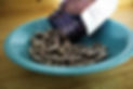 Placenta capsules in a teal bowl resting on a wooden surface