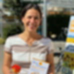 Claudia Sommer lächelt, hält Flyer "Auf den Punkt gebracht" und Rose