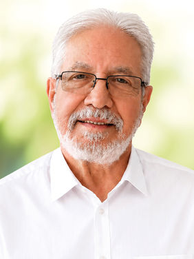 Ein Kandidat mit grauem Haar, Brille und weißem Hemd.
