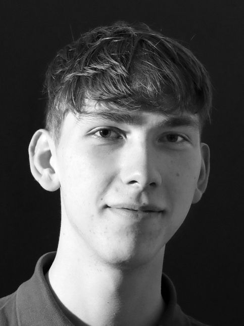Schwarz-weiß Porträt eines jungen Mannes mit dunklen Haaren lächelnd.