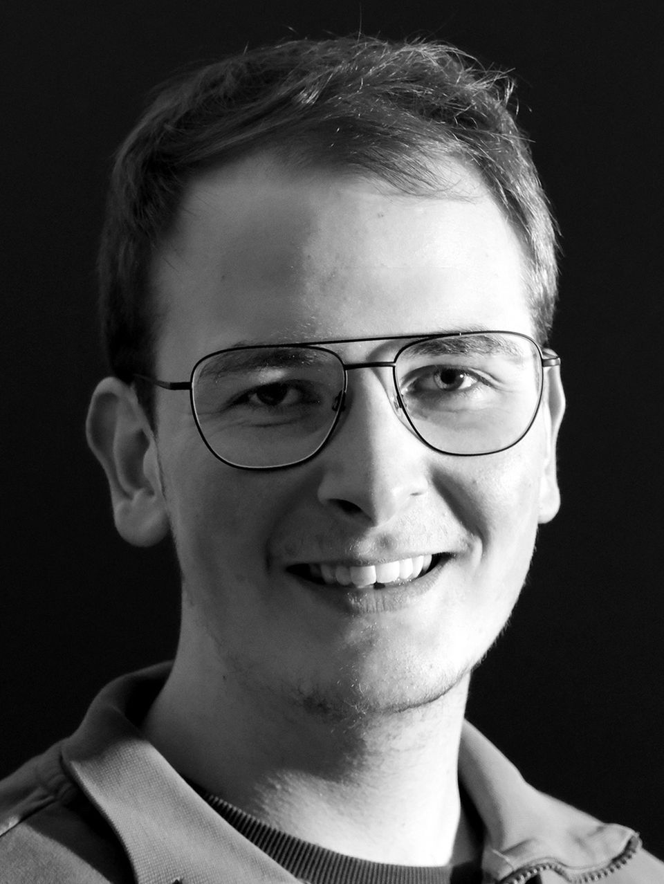 Schwarz-weiß Porträt eines lächelnden Mannes mit Brille.