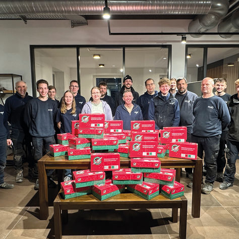 Teamfoto mit vielen gepackten Weihnachtsschuhkartons auf einem Tisch