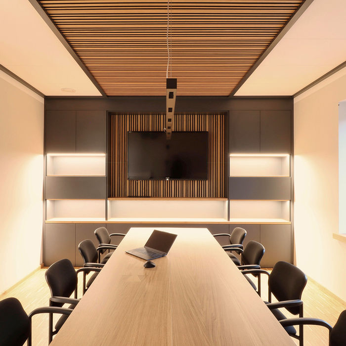 Elegantes Besprechungszimmer mit Holztisch, Stühlen, Bildschirm und Holzdecke.