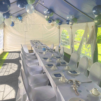 Festzelt innen, mit langem, gedecktem Tisch und Ballons.