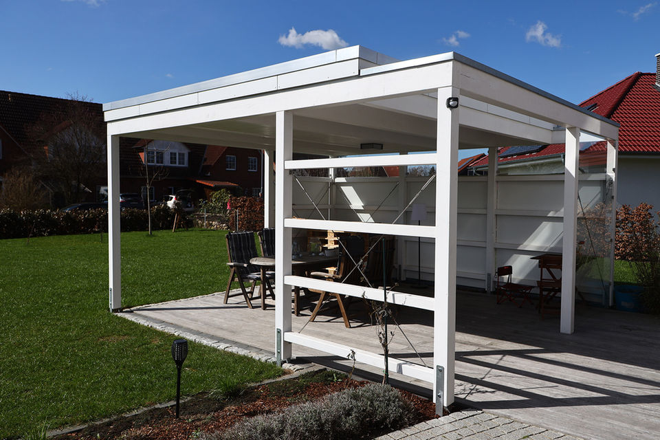 Weißes Gartenhaus mit Stühlen und Tisch, grüne Wiese