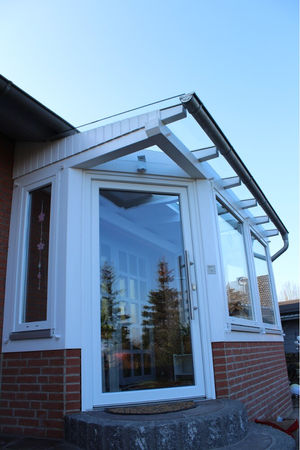 Moderner Eingang mit Glasdach und weißem Holzrahmen