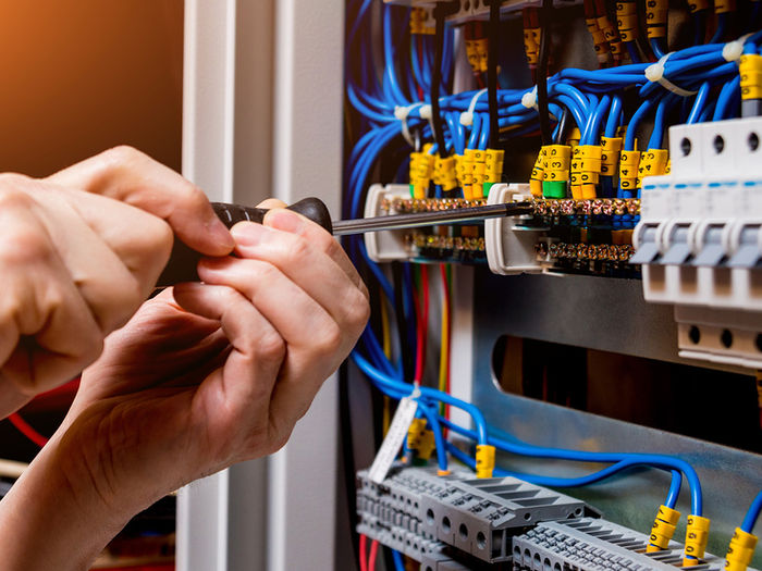 Elektriker arbeitet mit Schraubendreher an einer Schaltanlage: Zum Stellenangebot Elektroniker