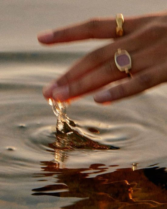 hand with gold rings dipping into the water